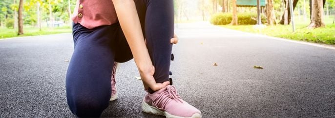 Female teenager hand touching painful twisted or ankle sprain,fe