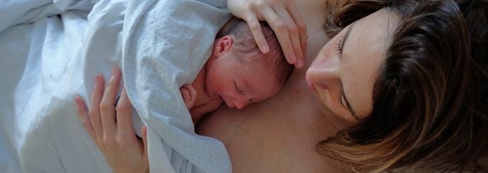 Mother Embracing Her Newborn Baby on the Bed