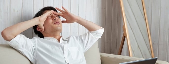 Men exhibit signs of stress while working on laptops, reflecting work-related mental burdens.