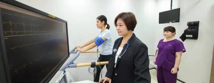 Female patient performing a treadmill stress test under supervision of medical staff, highlighting the importance of cardiovascular screening in women’s health check-ups.