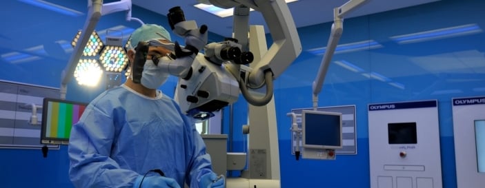 Surgeon performing surgery using specialised surgical equipment in an operating room.