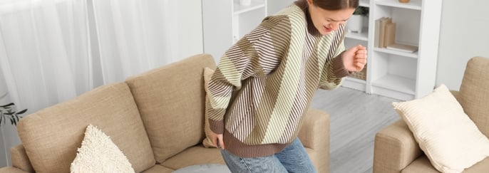 女子坐下時感到臀部不適，示意痔瘡相關疼痛或刺激。