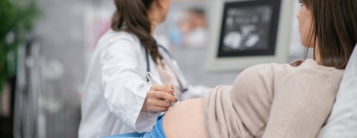 Obstetrician performing an ultrasound scan on a pregnant woman, illustrating prenatal check-up and foetal monitoring
