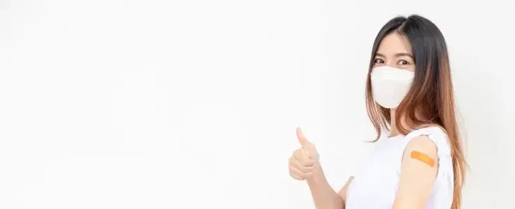Woman wearing a face mask showing a bandage after vaccination.