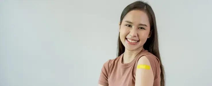 Woman showing a bandage on her upper arm after receiving a vaccination.
