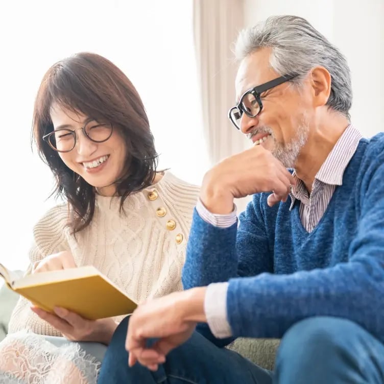 cheerful asian couple reading book