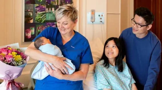 nurse caring for baby with mother and father looking on