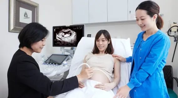 obstetrician doing an ultrasound for a mother with nurse looking on
