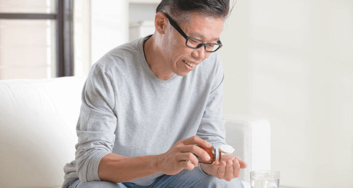 asian male pouring medicine pill onto his hand