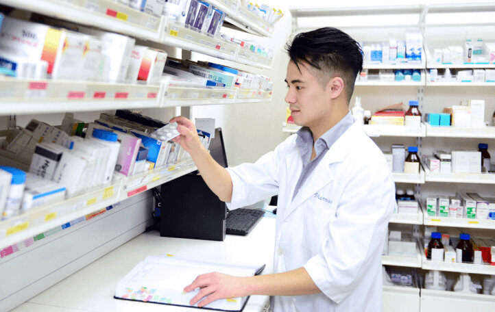 male pharmacist picking out medicine in pharmacy